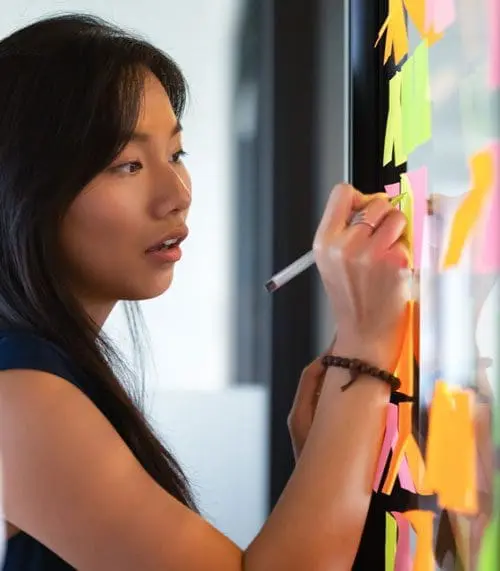 woman writing on post-it notes img